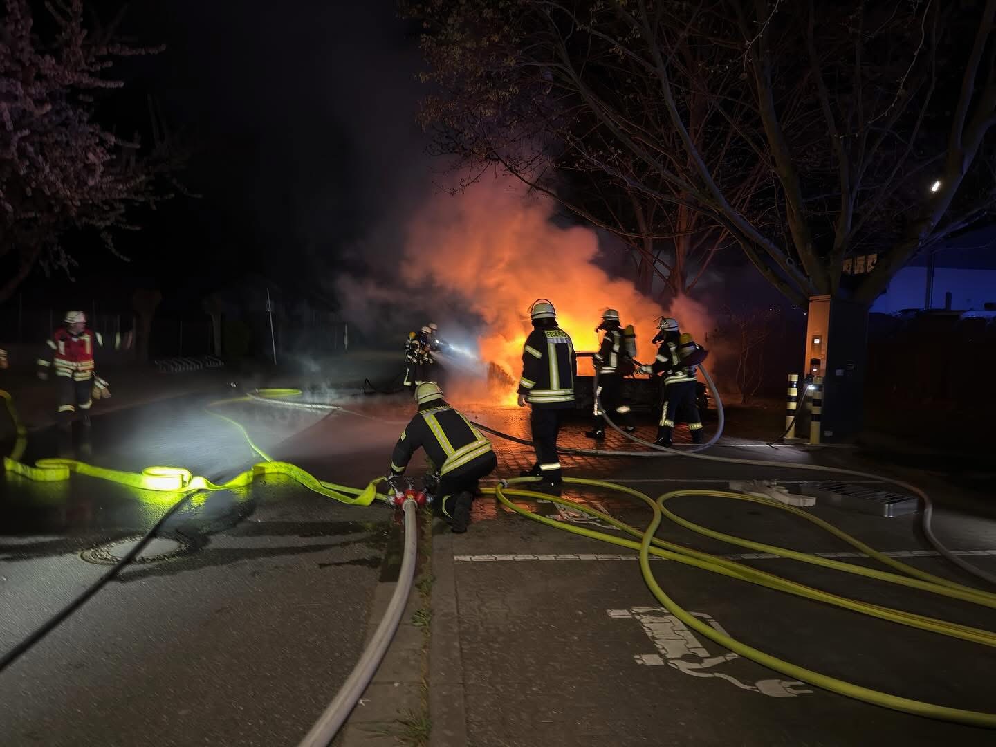 Feuerwehrkräfte bei einem Fahrzeugbrand in der Nacht